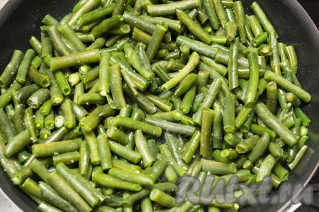 Обжарить фасоль на огне чуть выше среднего, не накрывая крышкой и периодически перемешивая, в течение 10 минут. К этому времени фасоль полностью разогреется, посолить её по вкусу, добавить любимые специи, перемешать. Сделать огонь ниже среднего, накрыть сковороду крышкой и продолжить тушить фасоль в течение 7 минут. За это время можно 2-3 раза перемешать. Если стручковая фасоль будет приставать ко дну сковороды в процессе тушения, тогда можете влить 2-3 столовых ложки воды.
