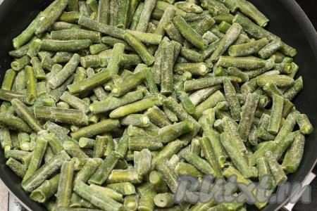 На сковороде хорошо разогреть растительное масло, затем выложить замороженную стручковую фасоль.