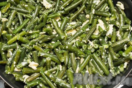 В сковороду со стручковой фасолью влить небольшими порциями яичную смесь, аккуратно перемешивая стручки. В процессе перемешивания все стручки должны быть покрытыми яйцами.