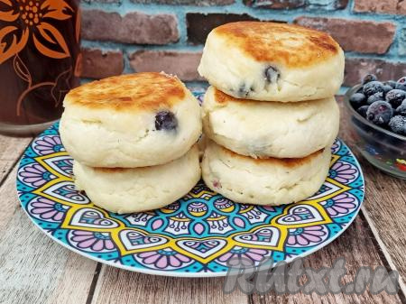 Готовые пышные, воздушные сырники с ягодами горячими подать к столу.