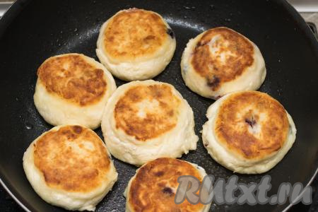 Затем сырники перевернуть, накрыть сковороду крышкой. Готовить сырники ещё 2-3 минуты (до подрумянивания с нижней стороны). Ещё раз перевернуть сырники и потомить под крышкой на небольшом огне 2 минуты. Выключить огонь и дать сырникам постоять под крышкой 5-8 минут, чтобы хорошо прогрелись замороженные ягоды.
