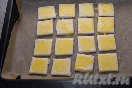 С помощью кулинарной кисточки смазать поверхность каждого квадратика из теста взбитым желтком.&nbsp;