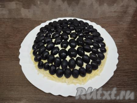 Маслины разрезаем пополам.&nbsp;Выкладываем половинки маслин на салат по кругу, низ салата выкладывать маслинами не нужно, потому что по низу салата будем вставлять чипсы.&nbsp;