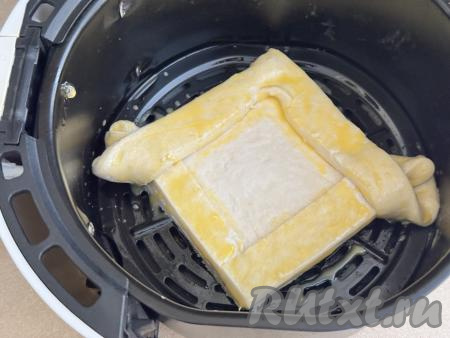 Решётку аэрогриля смазать растительным маслом (или застелить пергаментом), выложить заготовку хачапури. В небольшой чашке венчиком взбить яичный желток вилкой до однородности. Бортики хачапури с помощью силиконовой кисточки смазать взбитым желтком.