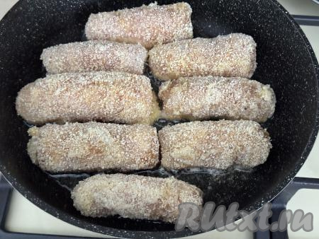 В сковороду влить растительное масло, хорошо его разогреть, уменьшить огонь до среднего, выложить куриные рулетики с сыром.