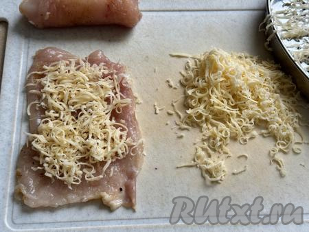 Сыр натереть на мелкой тёрке. Зрительно разделить сыр на 10 равных частей (по количеству рулетиков, которые будем формировать). Взять один отбитый кусок мяса, выложить одну часть натёртого сыра, оставляя с одного более узкого края мяса 1-2 сантиметра без сыра.