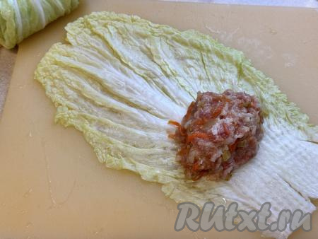 Лист китайской капусты выложить на доску и слегка отбить утолщённую часть листа. Начинку разделить на 8 частей. Выложить одну часть начинки ближе к узкой части листа, обязательно отступая от краёв листа.&nbsp;