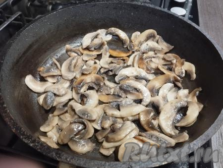 На сковороде разогреваем 2 столовых ложки растительного масла, выкладываем шампиньоны, на огне выше среднего обжариваем грибы до готовности (в течение 6-7 минут), периодически перемешивая. Вода из грибов должна выпариться. В процессе обжаривания шампиньоны солим. Жареные грибы убираем с огня, даём немного остыть.