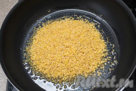 В сковороде прогреть 2 столовых ложки растительного масла, всыпать булгур.