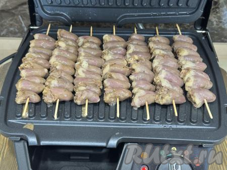 Створки электрогриля смазать растительным маслом. Выставить на электрогриле режим № 2 "Сосиски, Бутерброды", хорошо разогреть. Выложить шашлычки из куриных сердечек на шпажках в один слой на нижнюю панель электрогриля. Накрыть электрогриль верхней панелью.