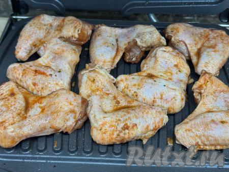 Разогреть электрогриль, выставить режим № 2 "Мясо". Смазать створки электрогриля растительным маслом, выложить подготовленные крылышки в один слой.