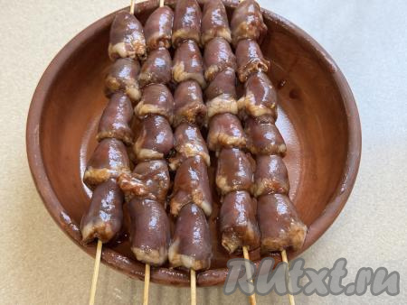 Минут за 30 до начала приготовления шашлычков, нужно выложить деревянные шпажки в достаточно глубокую ёмкость, полностью залить холодной водой. Оставить шпажки в воде минут на 30. Благодаря предварительному замачиванию, шпажки не будут тлеть в процессе приготовления шашлычков в духовке. После того как сердечки промаринуются в течение часа, нанизать их на шпажки. Я сформировала 5 шашлычков на деревянных шпажках. Сформированные шашлычки выложить на бортик любой формы для запекания так, чтобы сердечки находились в подвешенном состоянии, как на фото.&nbsp;