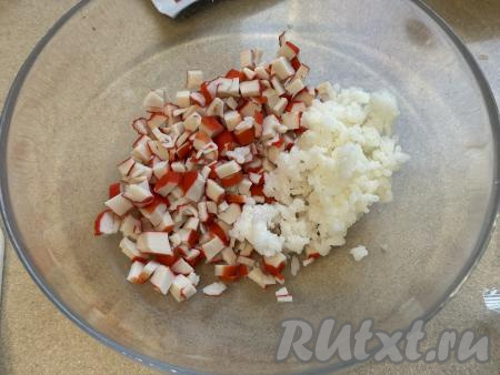 Крабовые палочки освободить от упаковки, мелко нарезать. В миске соединить варёный рис и нарезанные крабовые палочки.