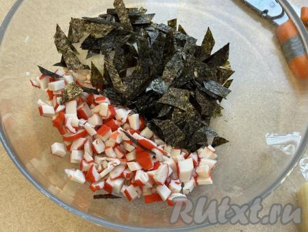 Листы нори нарезать ножницами на небольшие кусочки и добавить в миску с крабовыми палочками и рисом.