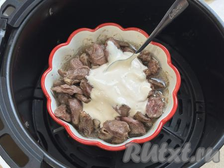 По истечении 20 минут достать чашу из аэрогриля, в форму с куриными сердечками добавить сметану.&nbsp;