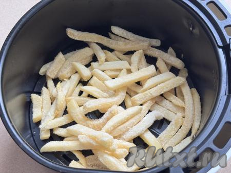 На решётку в чашу аэрогриля выложить замороженную картошку. Не перегружайте чашу, нормальная порция картофеля 250 грамм. Эта картошка продаётся уже смешанная с маслом, поэтому перед запеканием её маслом смазывать не нужно.