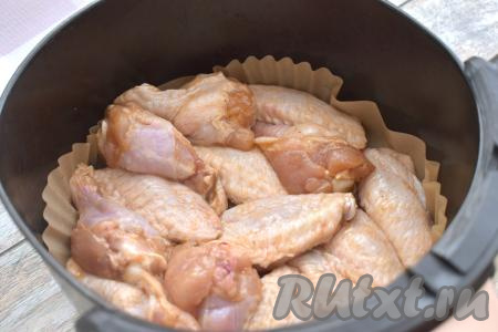 Минут через 30 куриные крылышки, пропитавшиеся медовым соусом, в один слой выкладываем в чашу аэрогриля, застеленную пергаментом. Отправляем чашу в аэрогриль. Включаем аэрогриль на 190 градусов, время устанавливаем 30 минут.