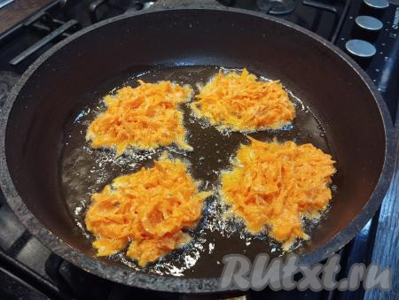 На сковороде разогреваем растительное масло, убавляем огонь до среднего. Столовой ложкой выкладываем по 1 столовой ложке морковного теста, накрываем сковороду крышкой. Жарим драники до подрумянивания снизу (ориентировочно в течение 3-4 минут).
