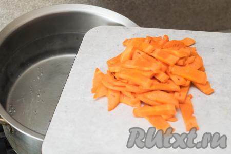 В кастрюлю с закипевшей водой выложить морковку, нарезанную на тонкие брусочки.