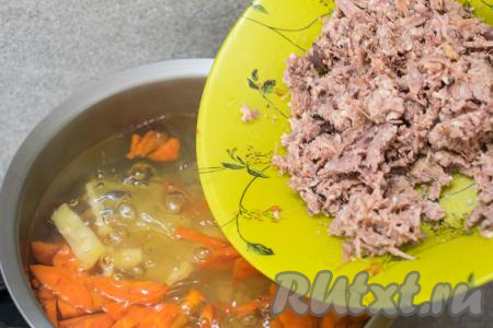 После того как картошка с морковью проварятся с момента закипания 15 минут, выложить в кастрюлю тушёнку, перемешать, дать закипеть.