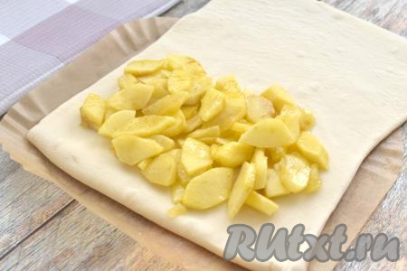 Отступая от краёв одной более узкой части прямоугольника примерно по 1 сантиметру, выкладываем остывшую начинку из яблок.