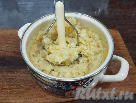 Кастрюлю со сварившейся картошкой убираем с огня. Всю воду, в которой варился картофель, из кастрюли сливаем. Разминаем картошку толкушкой до состояния пюре.