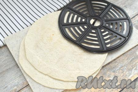 В первую очередь «подравниваем» лепёшки "Тортилья" под диаметр чаши аэрогриля. У меня тортильи были больше диаметра чаши аэрогриля, поэтому я с помощью кухонных ножниц обрезала их до нужного размера, используя в качестве ориентира решётку аэрогриля. У меня получились лепёшки диаметром 18 сантиметров.