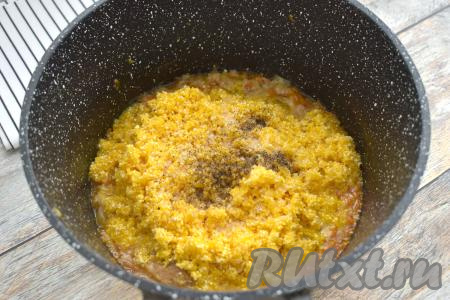 По прошествии 5 минут к овощам и тушёнке добавляем подготовленную кукурузную крупу, по вкусу солим, перчим.