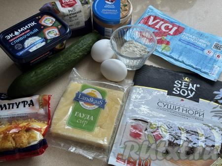 Подготовить продукты для приготовления суши-шариков в аэрогриле. Рыбную икру можно взять недорогую (например, щуки, мойвы, салаки). Крабовые палочки, если они заморожены, нужно разморозить. Рис заранее сварить до готовности или использовать 150 грамм уже отваренного риса. Для того чтобы отварить рис, его нужно промыть под проточной водой, лишнюю воду слить, затем переложить в кастрюлю, залить водой комнатной температуры в соотношении 1 к 2 (одна часть риса на две части воды), поставить на огонь. После закипания воды, добавив соль, варить рис на медленном огне под крышкой, не перемешивая, до готовности (ориентировочно в течение 20 минут). Готовый рис остудить.