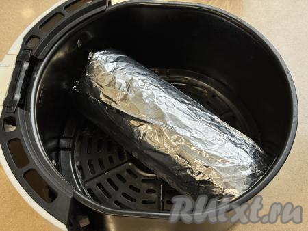 Рулет из фарша с яйцом, завёрнутый в пергамент, завернуть в лист фольги. Закрутить края фольги с двух сторон. Рулет, завёрнутый в фольгу, будет напоминать конфету, выложить его на решётку в чашу аэрогриля. Отправить чашу в аэрогриль.