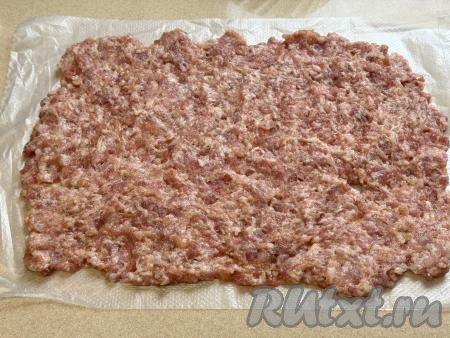 На столе расстелить целлофановый пакет, на него выложить фарш и распределить его в пласт толщиной чуть меньше 1 сантиметра.