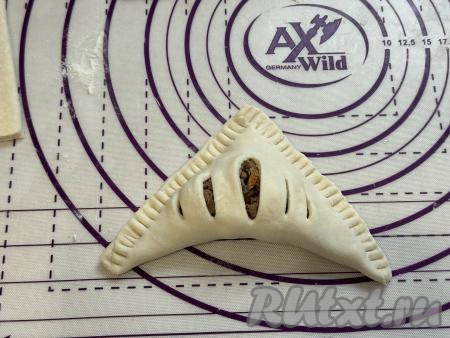 Углом теста с разрезами накрыть угол с печёночной начинкой, в результате получится треугольная заготовка слойки. Хорошо скрепить края слойки при помощи вилки. Если зубцы вилки будут сильно липнуть к тесту, тогда можно припорошить концы вилки мукой.&nbsp;