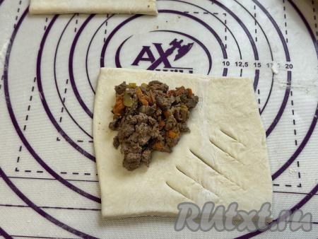 Я сразу разделила начинку на 8 частей - по количеству будущих слоек.&nbsp;Немного раскатать каждый квадратик теста. У меня получились квадраты со стороной 15 сантиметров. Ближе к одному краю квадрата, отступив от краёв по 1 сантиметру, выложить одну часть начинки из печёнки и овощей. На краю квадрата, который противоположен углу квадрата с начинкой, сделать несколько разрезов, как на фото.