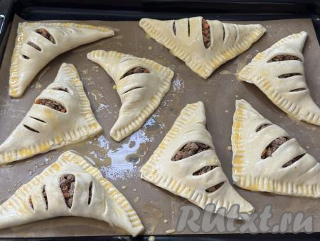 В небольшой ёмкости взбить вилкой яйцо до однородности. Смазать верх слоек взбитым яйцом.