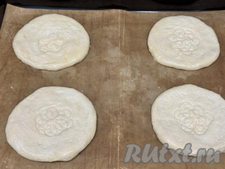 Растянуть каждую часть теста руками в круг толщиной примерно 0,5 сантиметра. В результате у меня получились 4 лепёшки диаметром 13 сантиметров. Выложить получившиеся лепёшки на противень, застеленный ковриком (или пергаментом) для выпечки. Серединку каждой лепёшки наколоть вилкой или прижать трафаретом для выпечки (я использовала трафарет в виде цветка).