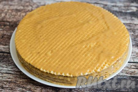 Таким образом собрать весь торт из вафельных коржей со сгущёнкой и бананом, не забывая смазать кремом и верхний корж. Оставшимся кремом (его остаётся немного) смазать бока торта. Готовый торт накрыть (я накрыла крышкой от микроволновки) и поместить, как минимум, на 2 часа в холодильник. В холодильник поместить и шоколад для дальнейшего украшения, чтобы он стал холодным.