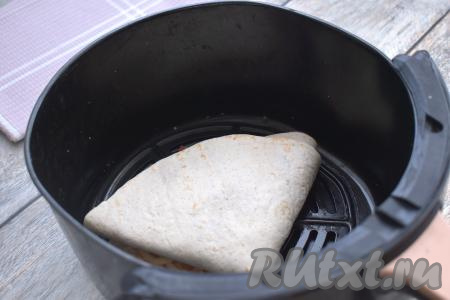 Тортилью с начинкой из колбасы и сыра выкладываем на решётку в чашу аэрогриля. У меня поместилась только одна лепёшка, поэтому я готовила в два захода. Отправляем чашу в аэрогриль. Устанавливаем температуру 180 градусов, время - 6 минут. Этого времени достаточно, чтобы сыр внутри лепёшки расплавился. Готовую тортилью выкладываем из чаши аэрогриля на тарелку. Я готовила в аэрогриле мощностью 1400 Ватт с одним ТЭН-ом.