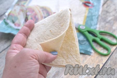 Лепёшки "Тортилья" продаются практически в любом продуктовом магазине. В этот раз я купила тортильи диаметром 25 сантиметров. Вначале одну лепёшку складываем пополам, затем ещё раз складываем пополам. Благодаря предварительному сгибанию, в дальнейшем лепёшку с начинкой будет проще сгибать перед запеканием в аэрогриле. Один сгиб лепёшки разрезаем кулинарными ножницами до центра.