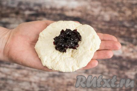 Выложить в середину творожной лепёшки 1 чайную ложку начинки из густого варенья (у меня - варенье из чёрной смородины). Напомню, что жидкое варенье нужно заранее подморозить, чтобы оно держало форму и выкладывать в охлаждённом виде.