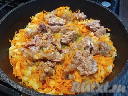 К обжаренным морковке и луку добавляем тушёнку, перемешиваем и обжариваем 5 минут, перемешивая и равномерно распределяя кусочки мяса.