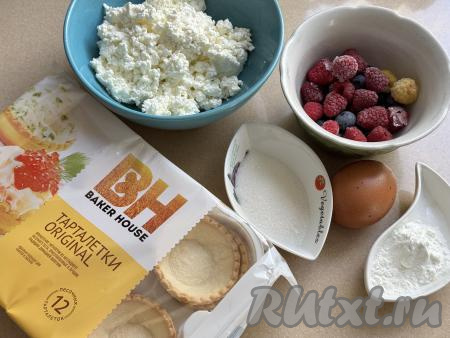Подготовить продукты для приготовления тарталеток с творогом и ягодами в духовке. Творог можно использовать любой жирности (у меня - жирностью 5%). Крахмал моно взять как кукурузный, так и картофельный. Ягоды можно взять любые как свежие, так и замороженные. Если вы возьмёте ягоды с крупными косточками (например, вишню, черешню), значит косточки нужно удалить. Свежие ягоды нужно будет промыть водой, обсушить, разложив их на бумажном полотенце. Если вы, как и я, возьмёте замороженные ягоды, на которых нет большого количества льда, значит их можно не размораживать.&nbsp;Песочные тарталетки можно купить практически в любом продуктовом магазине.