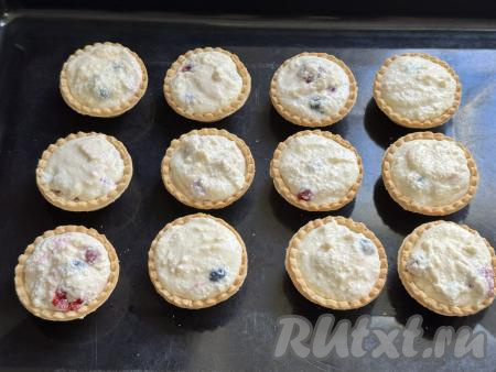 Разложить творожно-ягодную начинку по песочным тарталеткам, полностью заполняя их. Я заполнила 12 тарталеток. Поставить наполненные тарталетки на противень.&nbsp;