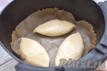 Чашу аэрогриля застилаем пергаментом, выкладываем пирожки с капустой «швом» вниз. У меня в чашу аэрогриля поместились только 3 пирожка с капустой, поэтому оставшиеся пирожки я выпекала во второй заход. В чашке взбиваем вилкой яйцо до однородности. С помощью силиконовой кисточки смазываем пирожки сверху взбитым яйцом. Отправляем чашу с пирожками в аэрогриль.