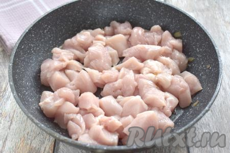 Куриное филе нарезаем на небольшие кубики, солим по вкусу, перемешиваем. В сковороду, в которой обжаривались шампиньоны, при необходимости добавляем немного растительного масла, прогреваем, затем выкладываем куриное филе. Обжариваем кусочки мяса курицы на среднем огне, периодически перемешивая, минут 10 (до лёгкого подрумянивания филе со всех сторон).