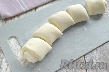 Размороженный пласт слоёного теста выкладываем на стол, присыпанный мукой. Не раскатывая, сворачиваем пласт слоёного теста в достаточно плотный. Разрезаем получившийся рулет на 5 частей.