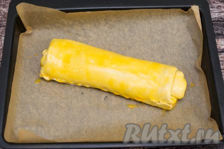 Отложенный ранее желток перемешать кулинарной кисточкой до однородности. Смазать при помощи кисти поверхность рулета желтком.