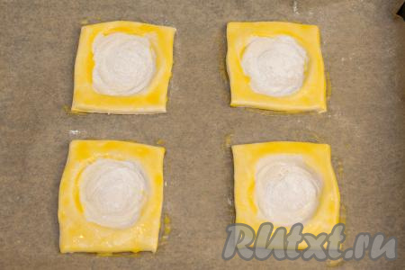 Ранее отложенный желток взбить вилкой до однородности. При помощи кулинарной кисти смазать взбитым желтком поверхность слоек, кроме углубления.