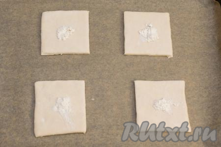 Противень застелить пергаментом. Переложить на противень 4 квадрата из слоёного теста. В центр каждого квадрата выложить по 1/4 чайной ложки муки.