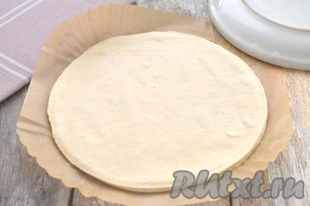 Размороженный пласт слоёного теста выкладываем на стол, присыпанный мукой, раскатываем до толщины 3-4 миллиметра. Вырезаем круг, диаметр которого должен&nbsp;быть на 2 сантиметра больше диаметра чаши вашего аэрогриля. Я вырезала круг диаметром 20 сантиметров, приложив поверх раскатанного теста перевёрнутую тарелку диаметром 20 сантиметров.&nbsp;В дальнейшем в процессе выпечки в аэрогриле курник нужно будет переворачивать, поэтому я рекомендую выпекать этот пирог на специальном вкладыше для аэрогриля из пергамента (или вырезать из пергамента для выпечки круг подходящего диаметра, чтобы он застилал и дно, и часть боковых стенок аэрогриля). Бумажный вкладыш (или вырезанную пергаментную бумагу), немного смазываем растительным маслом, выкладываем вырезанный круг из слоёного теста.
