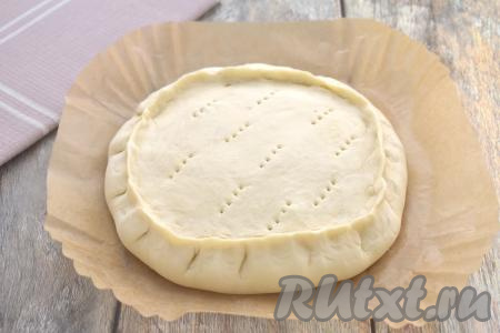 Слоёное тесто, оставшееся после вырезания круга диаметром 20 сантиметров, собираем. Эти остатки слоёного теста раскатываем в круг диаметром ориентировочно 18 сантиметров. Получившимся кругом из слоёного теста накрываем начинку, плотно скрепляем края пирога, как на фото. На поверхности курника делаем вилкой проколы, через которые будет выходить пар в процессе выпечки пирога в аэрогриле.